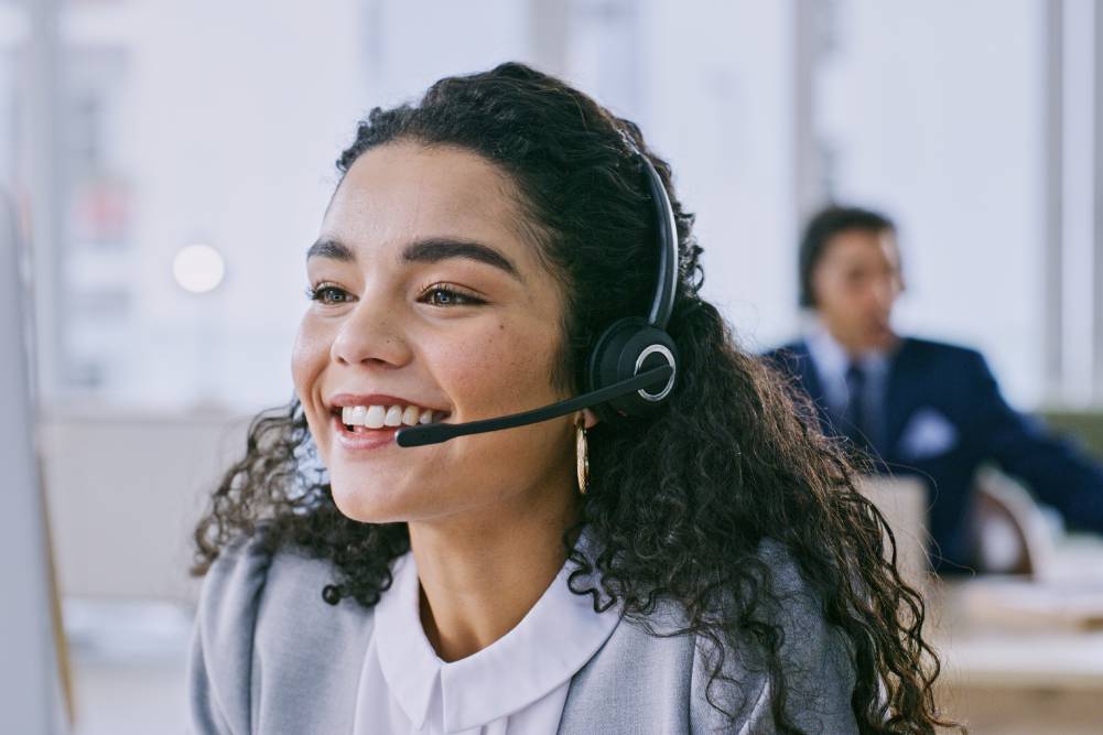 On-page, 2024. Customer service representative smiling while talking through a headset.