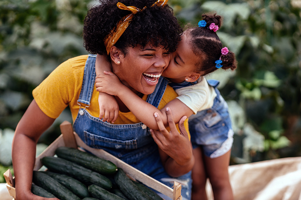 Little girl kissing mom on check outside. 