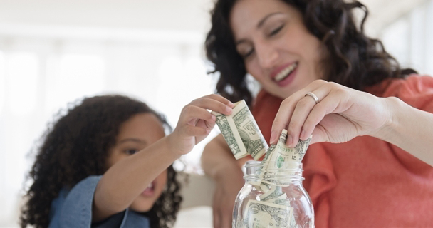 Mother and daughter putting money into a jar.