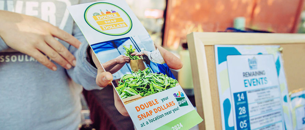 Woman holding Double SNAP Dollar brochure at farmer's market